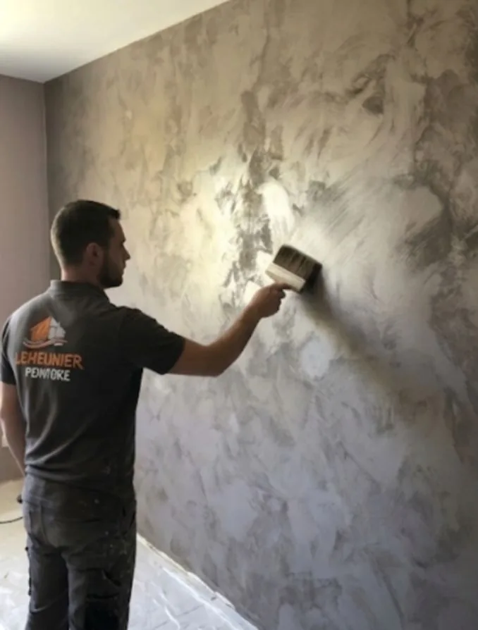 Un peintre de Lemeunier Rénovation applique à la brosse une finition décorative sur un mur