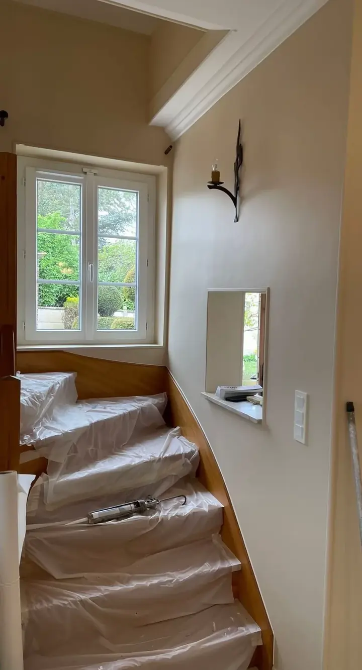 Escalier intégralement protégé par des bâches pendant un chantier de peinture