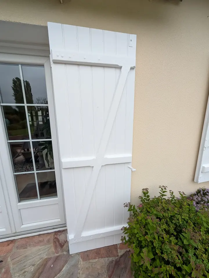 Volet en bois poncé et repeint en blanc sur une maison